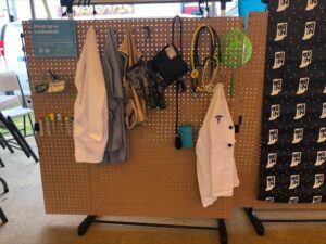 lab coats and other science equipment hanging next to all in for health set up desk 