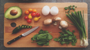 photo of a wooden cutting board with a knife and food