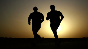photo of two men running with a sunset behind them